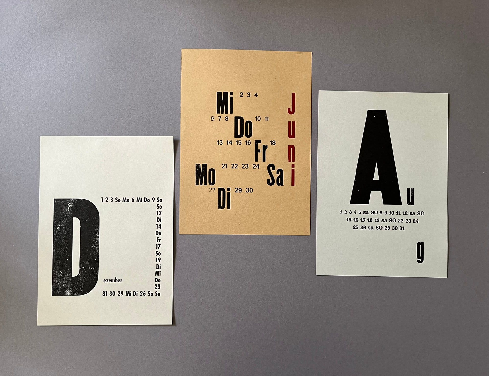 Drei Kalenderblätter mit großen Buchstaben und gesetzten Wochentagen