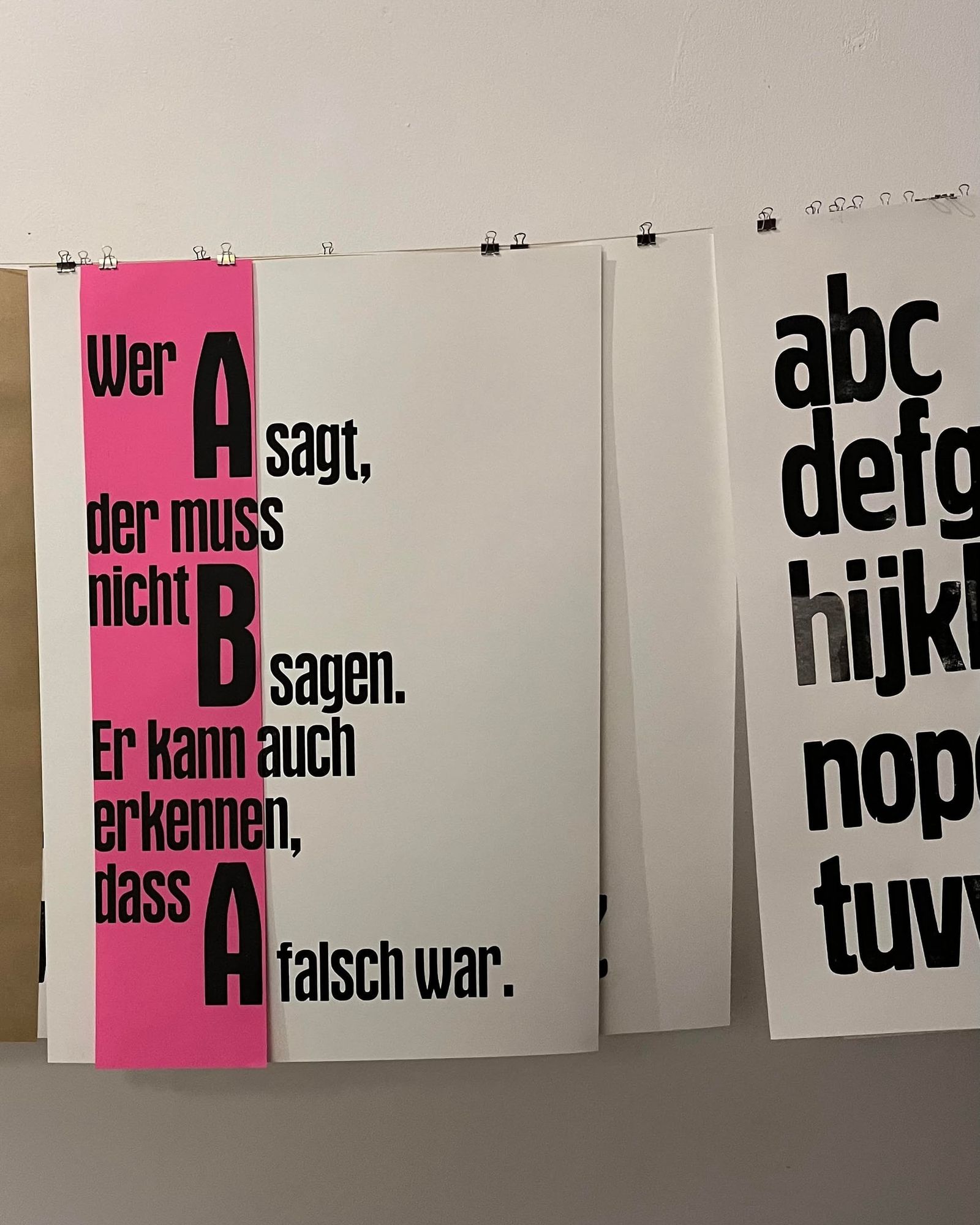 Plakate „Wer A sagt, der muss nicht B sagen“ an einer Leine, eines mit pinkem Streifen