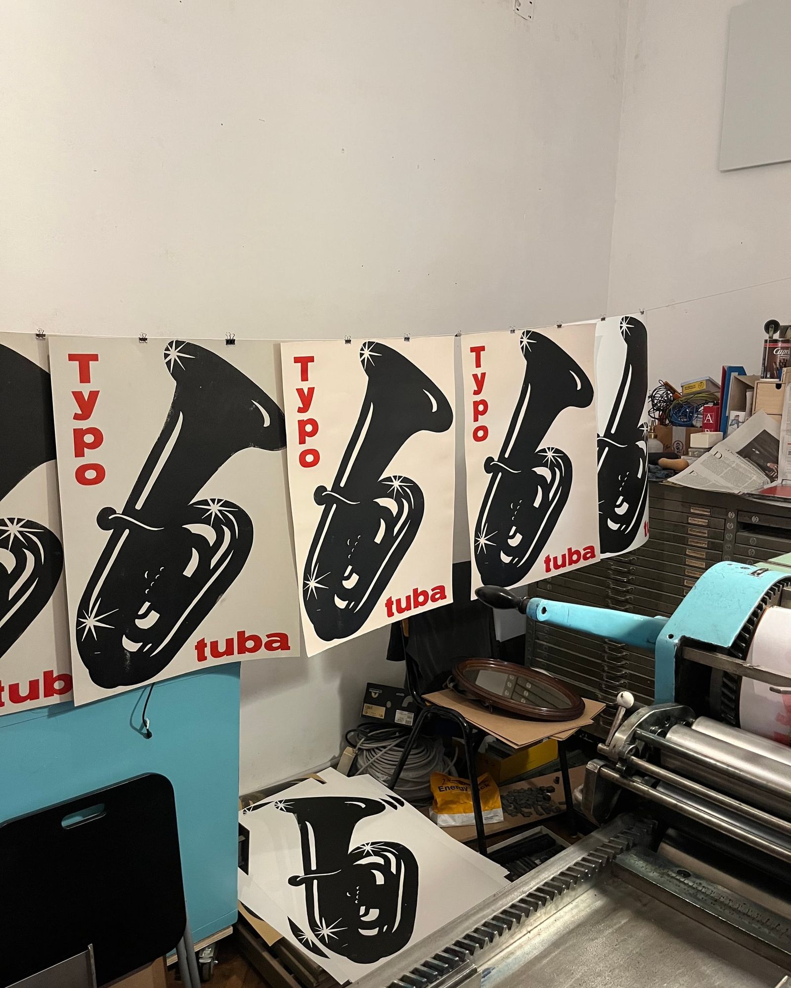 Druckmaschine in der Werkstatt, daneben frisch gedruckte Plakate mit einer Tuba