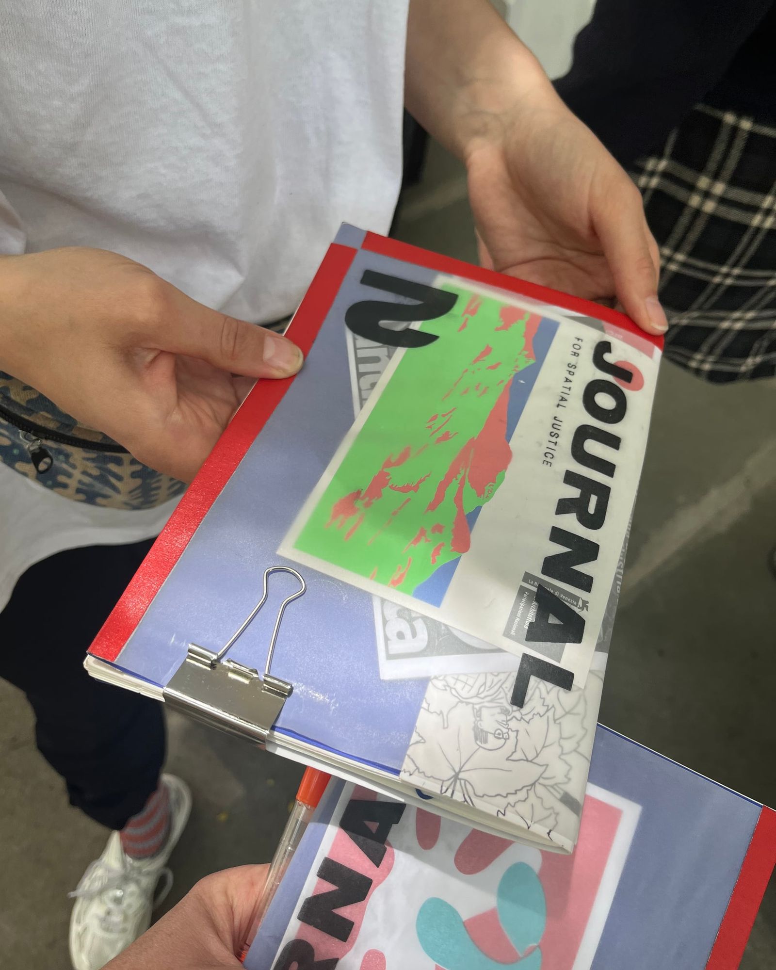 Hände halten ein gedrucktes Heft „Journal 2“ mit farbigem Umschlag